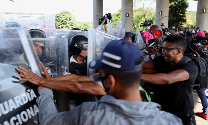 Illegal immigrants from Central America and Haiti clash with National Guard members as they walk in a caravan headed to the Mexican capital to apply for asylum and refugee status, in Tapachula, in Chiapas state, Mexico, on Oct. 23, 2021. (Jose Torres/Reuters)