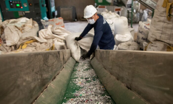 A worker loads shredded plastic to a machine to be molded into waterproof planks in the factory of  Plastic Flamingo or  Plaf, in Muntinlupa, Philippines, on Oct. 18, 2021. (Eloisa Lopez/Reuters)