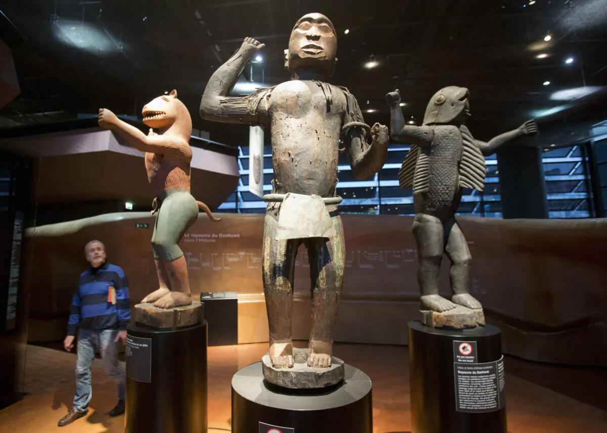 A visitor looks at wooden royal statues of the Dahomey kingdom, dated 19th century, at Quai Branly museum in Paris, France, on Nov. 23, 2018. (Michel Euler/AP Photo)