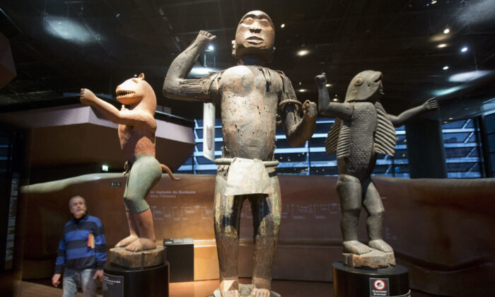 A visitor looks at wooden royal statues of the Dahomey kingdom, dated 19th century, at Quai Branly museum in Paris, France, on Nov. 23, 2018. (Michel Euler/AP Photo)