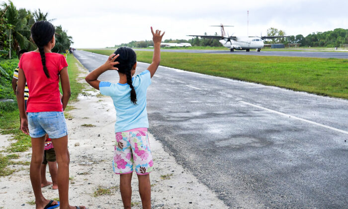 FUNAFUTI, TUVALU - AUGUST 15:  People gather at the airport three times a week to welcome and farewell passengers from Suva, Fiji on August 15, 2018 in Funafuti, Tuvalu.  siren is sounded to clear the runway of children, dogs, and motorbikes before the plane lands.  Tuvalu Government is trying to encourage its people to invest in tourism with grants for those wanting to start a tourist related business veture on the island.  small South Pacific island nation of Tuvalu is striving to mitigate the effects of climate change. Rising sea levels of 5mm per year since 1993, well above the global average, are damaging vital crops and causing flooding in the low lying nation at high tides. Sea water rises through the coral atoll on the mainland of Funafuti and inundates taro plantations, floods either side of the airport runway and affects peoples homes.  nation of 8 inhabited islands with an average elevation of only 2m above sea level is focusing on projects to help it and its people have a future. Four of the outer islands are 97% solar energy dependent and the Tuvalu Government is working to achieve 100% renewable energy from wind and solar by 2025. Tuvalu's 11,000 inhabitants see the effects of climate change in their daily life.  (Photo by Fiona Goodall/Getty Images for Lumix)