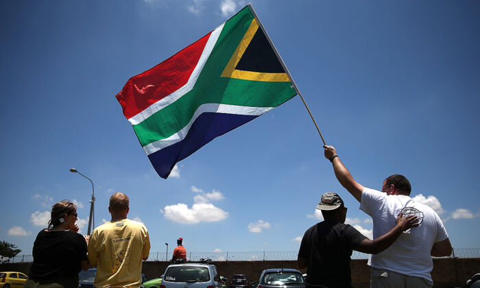 People wait alongside the road to see a military plane take off from Waterkloof military airbase that is carrying the casket of former South African President Nelson Mandela in Pretoria, South Africa, on Dec. 14, 2013. (Justin Sullivan/Getty Images)