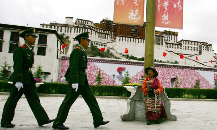 A Tibetan watches Chinese police officers patrolling in front of Potala Palace, in Lhasa, Tibet, on June 20, 2008. (Guang Niu/Getty Images)