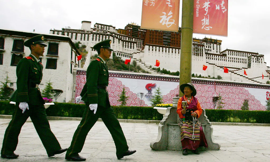 A Tibetan watches Chinese police officers patrolling in front of Potala Palace, in Lhasa, Tibet, on June 20, 2008. (Guang Niu/Getty Images)