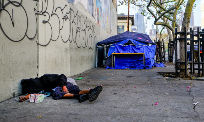 A homeless man sleep near tents in downtown Los Angeles on Nov. 18, 2018. (John Fredricks/The Epoch Times)