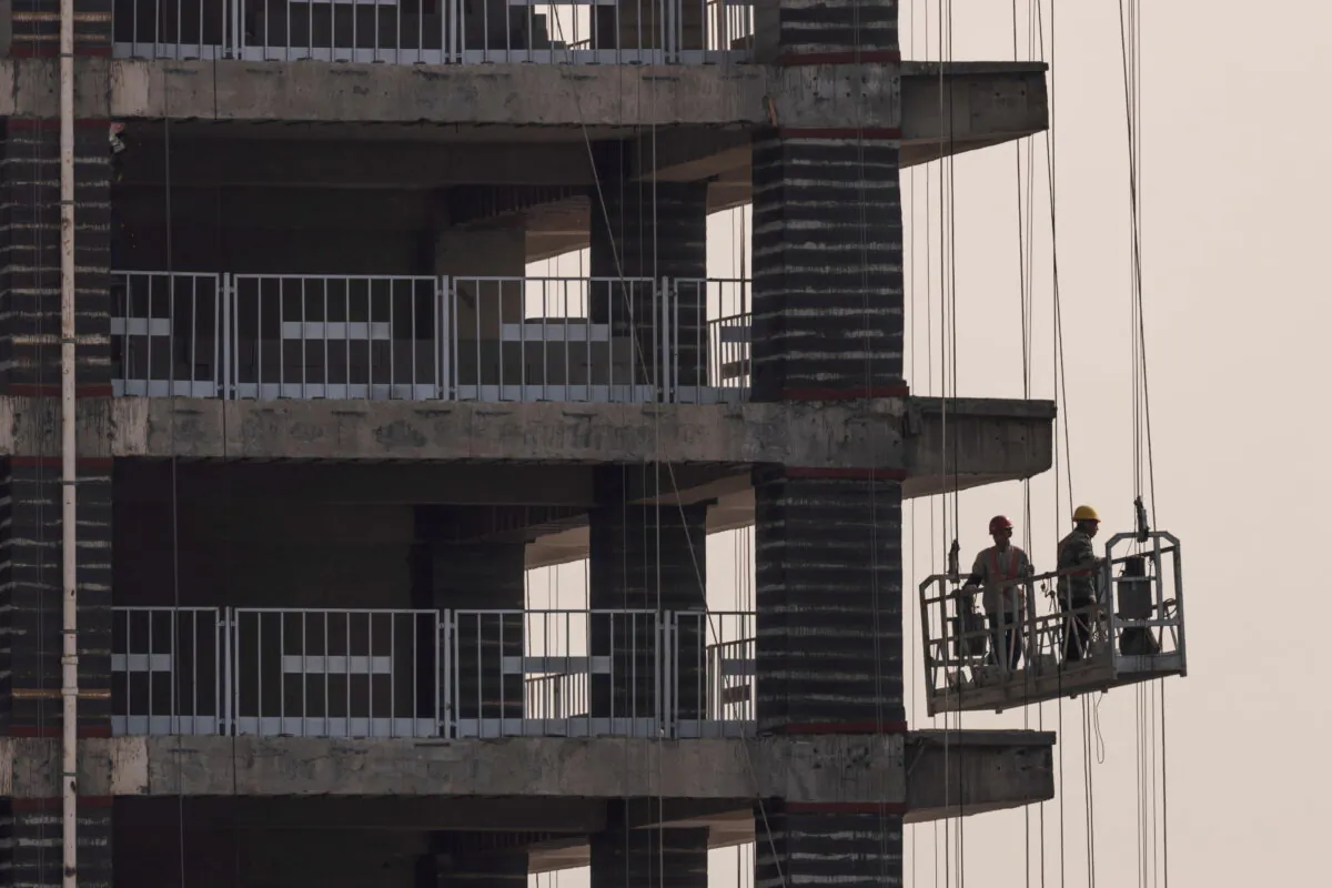 Men work at the construction site of a highrise building in Beijing, China, on Oct. 18, 2021. (Thomas Peter/Reuters)