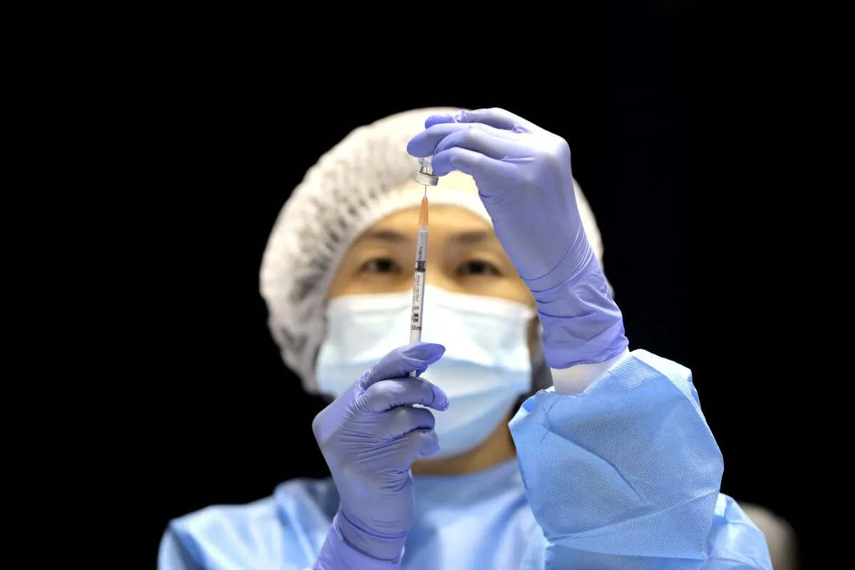 A health care worker fills a syringe with the Pfizer vaccine on the opening day of a COVID-19 mass vaccination clinic at the Perth Convention and Exhibition Centre in Perth, Australia on Aug. 16, 2021. (AAP Image/Richard Wainwright)