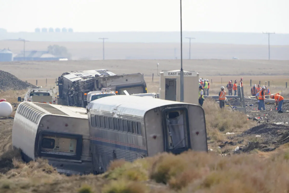 Workers stand near train tracks next to overturned cars from an Amtrak train that derailed near Joplin, Mont., on Sept. 27, 2021. (Ted S. Warren/AP Photo, File)