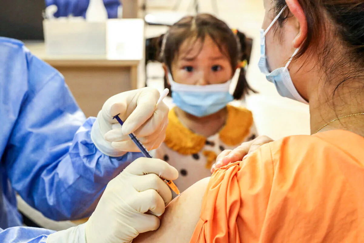 A child looking on as a woman receives the China National Biotec Group (CNBG) Covid-19 coronavirus vaccine in Nantong, in China's eastern Jiangsu Province,  on July 5, 2021. (STR/AFP via Getty Images)