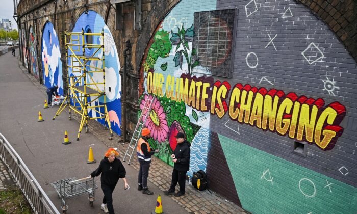 Artists paint murals on a wall near the Scottish Event Campus in Glasgow, Scotland, on Oct. 13, 2021, where the 26th U.N. Climate Change Conference will be held from Oct. 31 to Nov. 12. (Jeff J. Mitchell/Getty Images)