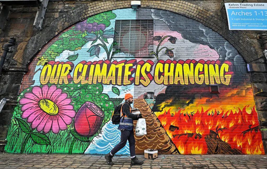 Artists paint a mural on a a wall next to the Clydeside Expressway near Scottish Events Centre (SEC) which will be hosting the COP26 UN Climate Summit in Glasgow, Scotland, on Oct. 13, 2021. (Jeff J Mitchell/Getty Images)