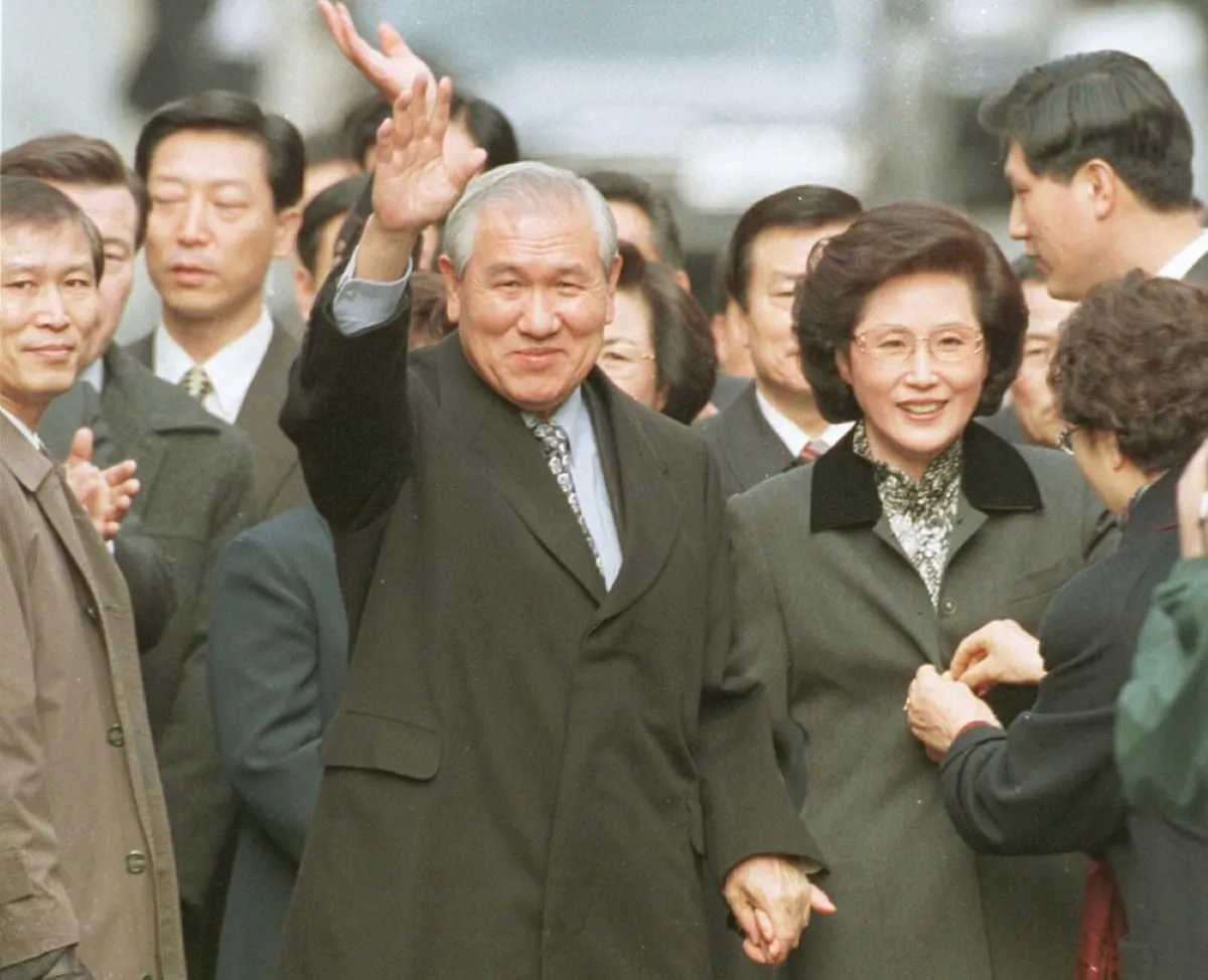 Former South Korean President Roh Tae-woo,
with his wife Kim Ok-sook standing beside him, waves to his supporters and neighbors upon arrival at his home, on Dec. 22, 1997. (Yonhap /AP Photo)