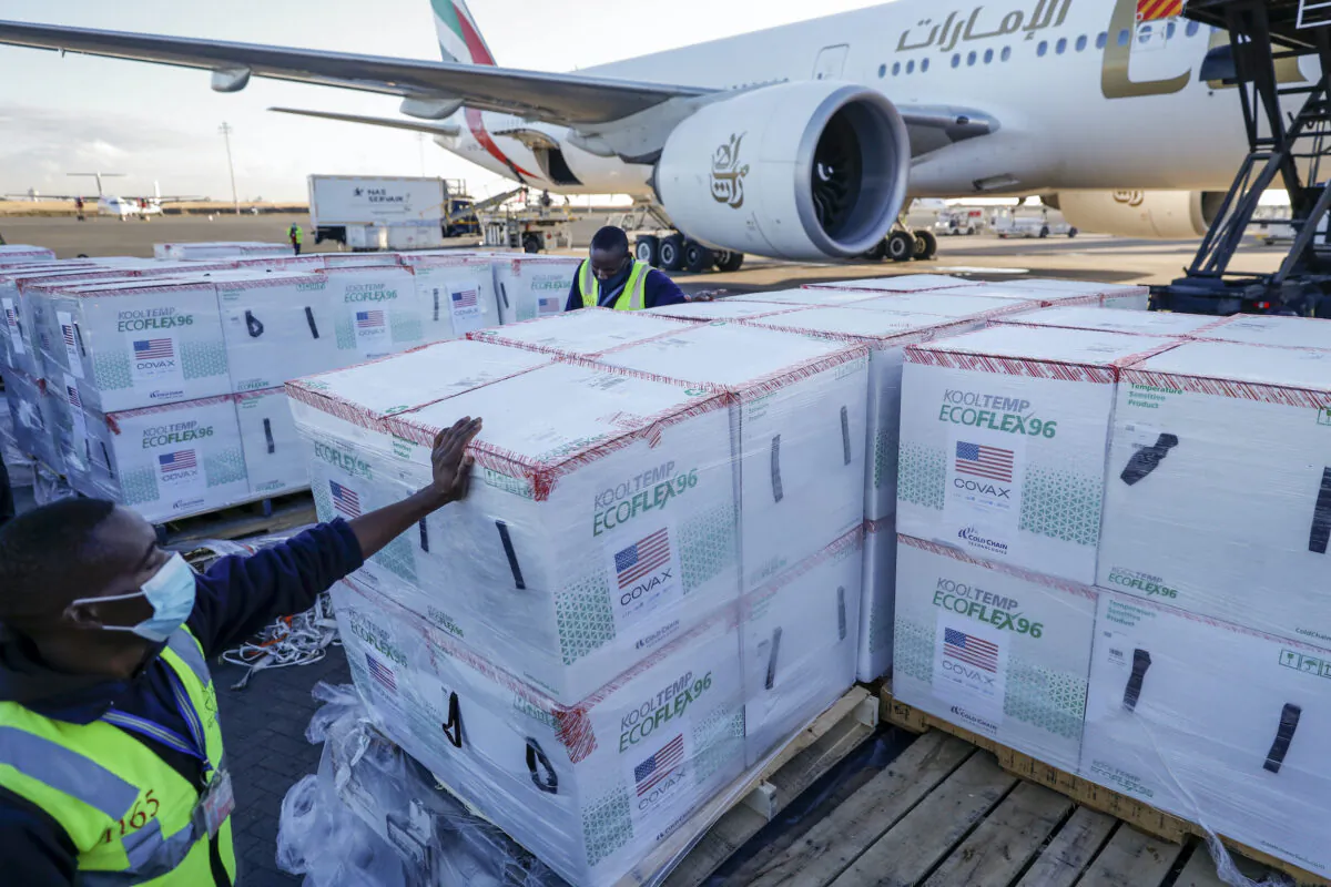 An airport worker stands next to boxes of Moderna coronavirus vaccine, donated by the U.S. government via the COVAX facility, after their arrival at the airport in Nairobi, Kenya, on Aug. 23, 2021. (Brian Inganga/AP Photo)