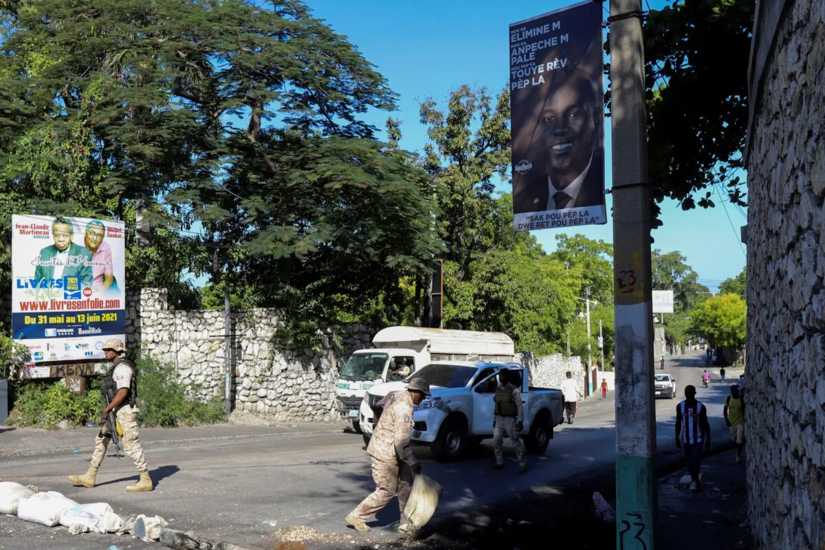 A sign with an image of assassinated President Jovenel Moise is seen as members of the Haitian National Police clear a street blockade set up in protest of insecurity and fuel shortages, in Port-au-Prince, Haiti, on Oct. 25, 2021. (Ralph Tedy Erol/Reuters)
