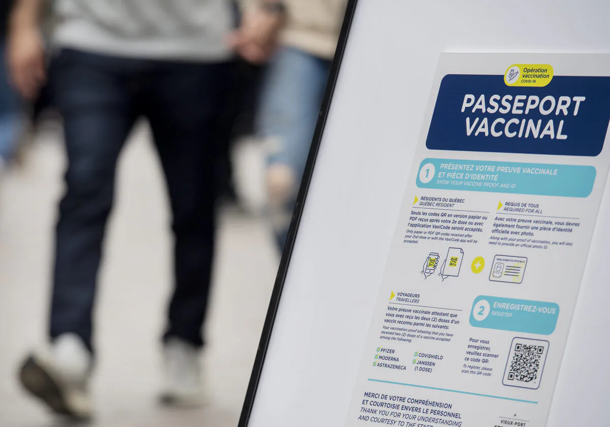 People walk by a sign at a restaurant advising customers of Quebec’s newly implemented COVID-19 vaccine passport in Montreal, on Sept. 6, 2021. (The Canadian Press/Graham Hughes)