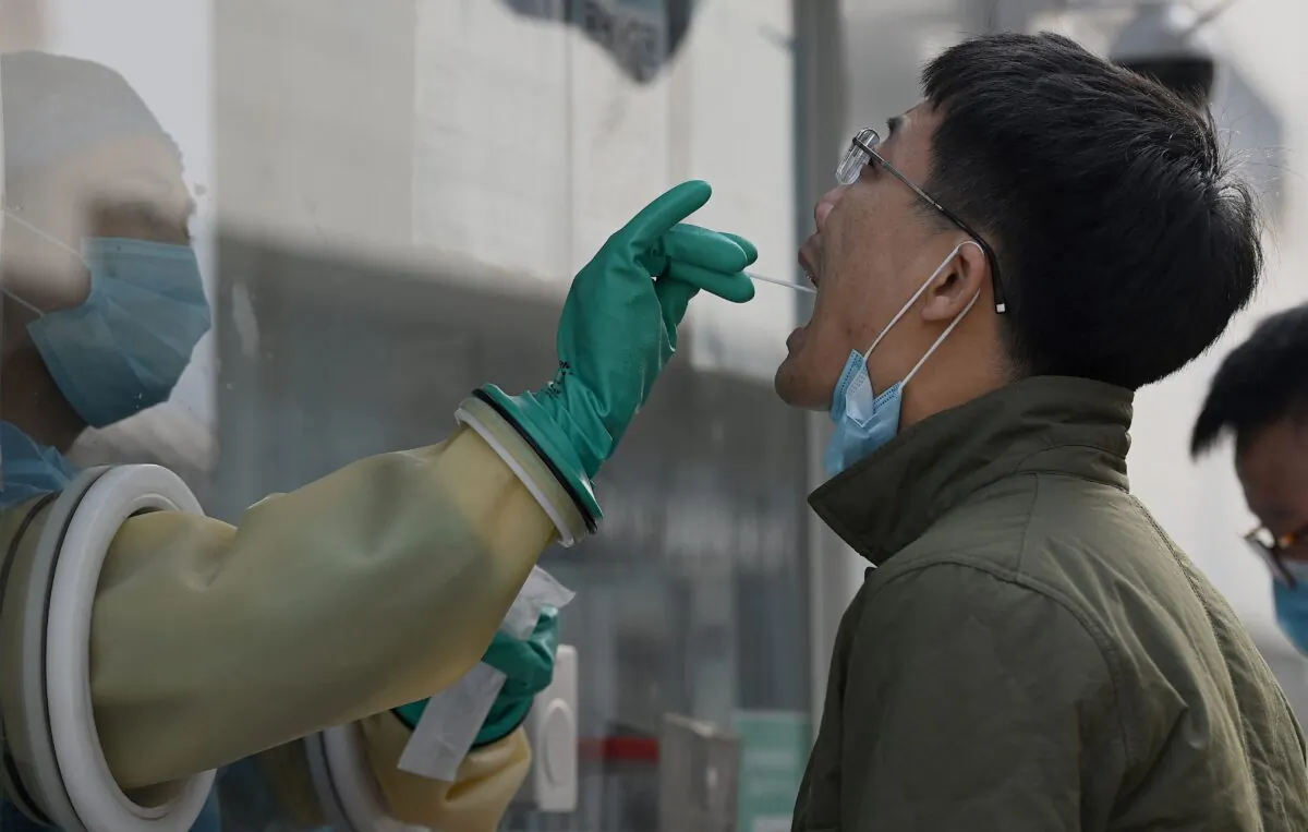 A health worker takes a swab for COVID-19 at a testing station in Beijing, China, on Oct. 25, 2021. (Noel Celis/AFP via Getty Images)
