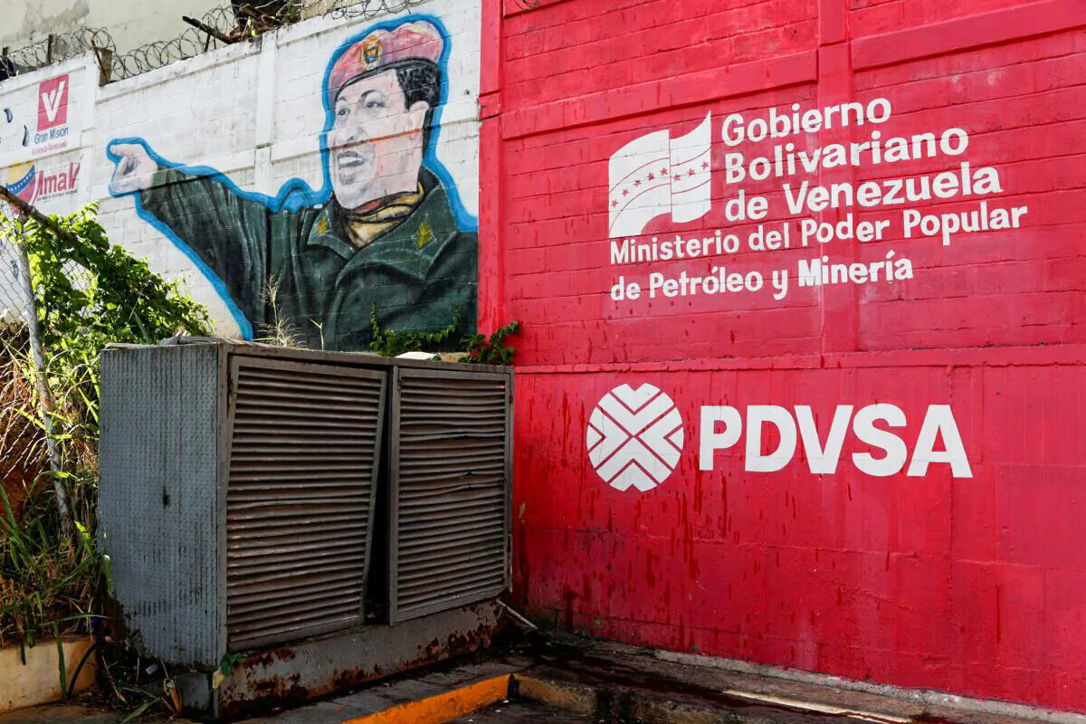 The logo of the Venezuelan state oil company PDVSA is seen next to a mural depicting Venezuela's late President Hugo Chavez at a gas station in Caracas, Venezuela, on March 2, 2017. (Carlos Garcia Rawlins/Reuters)