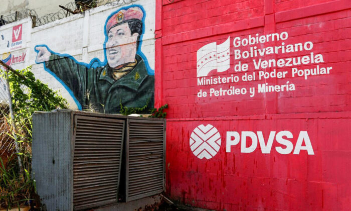   logo of the Venezuelan state oil company PDVSA is seen next to a mural depicting Venezuela's late President Hugo Chavez at a gas station in Caracas, Venezuela, on March 2, 2017.  (Carlos Garcia Rawlins/Reuters)