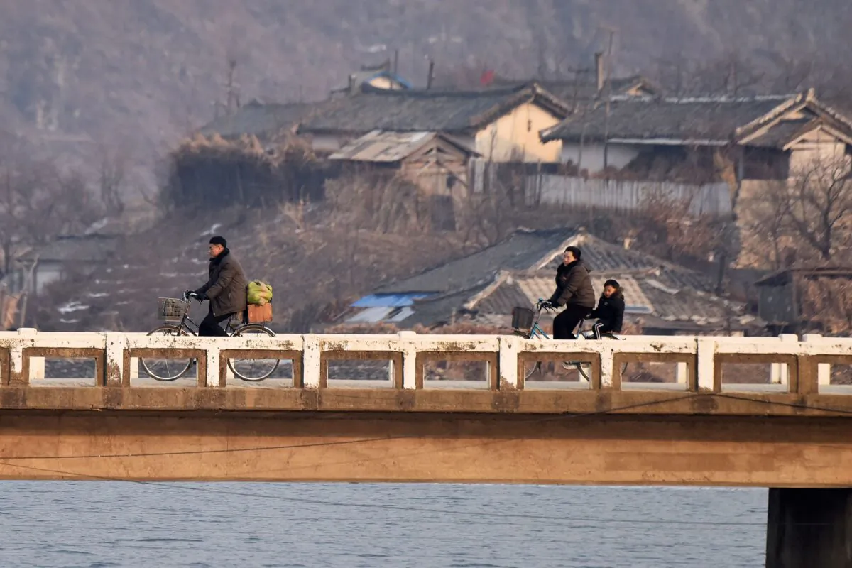 North Korean villagers ride bicycles on a bridge, as seen from a boat on the Yalu River, opposite Hekou, in China's northeast Liaoning Province, on Feb. 24, 2019. (Greg Baker/AFP via Getty Images)