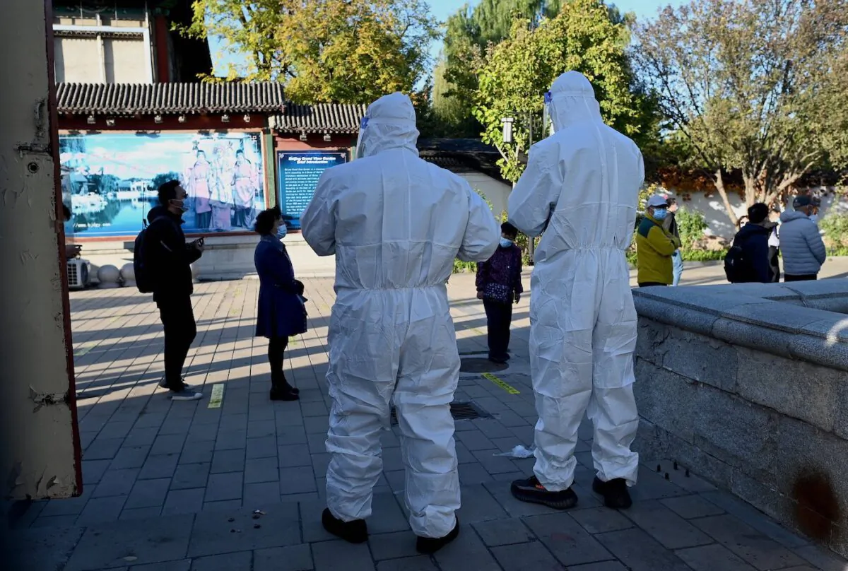 A health workers look at people queueing for swab tests for COVID-19 at a nucleic acid collection station in Beijing on Oct. 26, 2021. (Noel Celis/AFP via Getty Images)