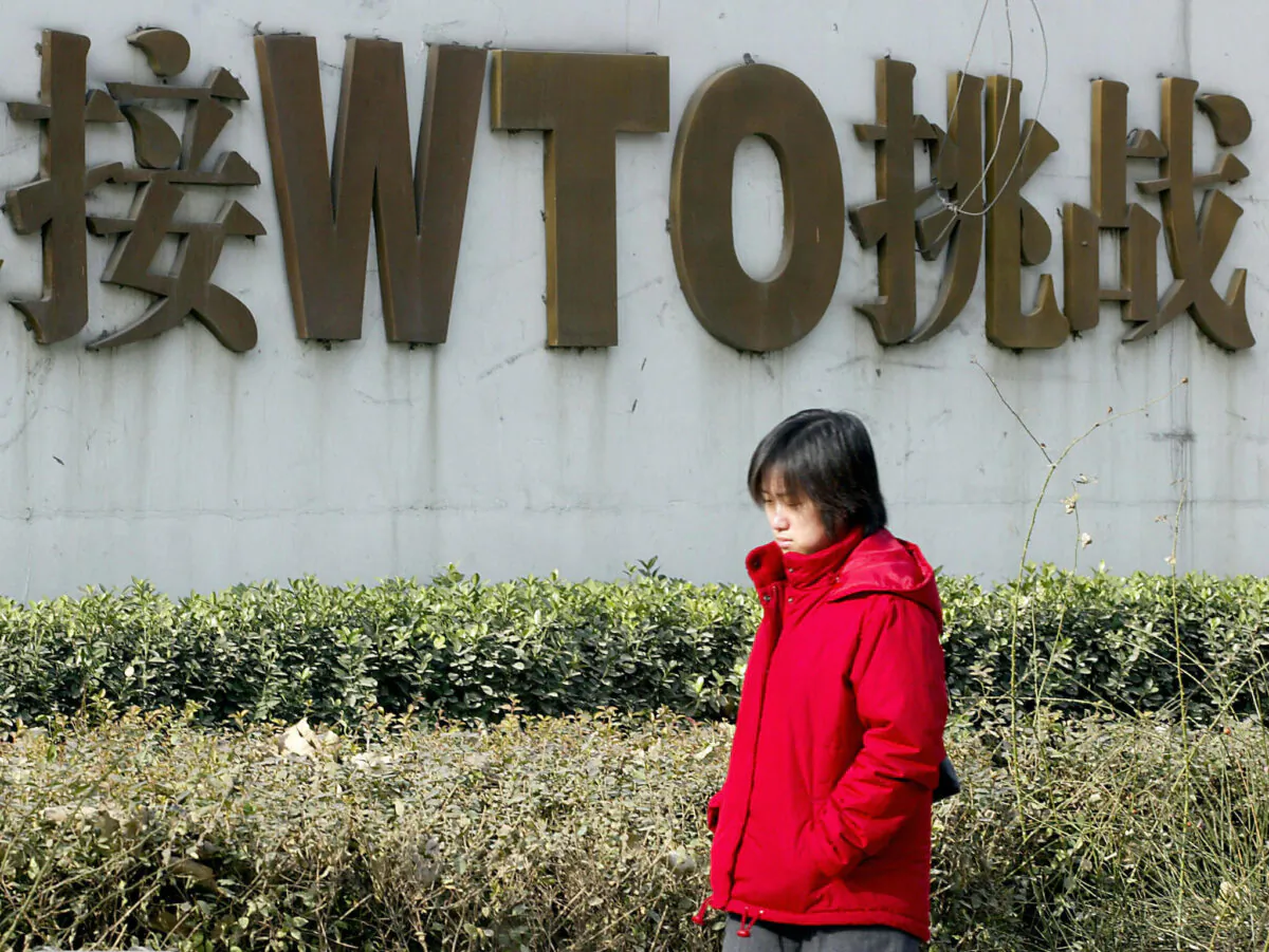 A Chinese woman walks pass a billboard boasting of China's World Trade Organization (WTO) membership along street in Beijing on Dec. 19, 2003. (Goh Chai Hin/AFP/Getty Images)