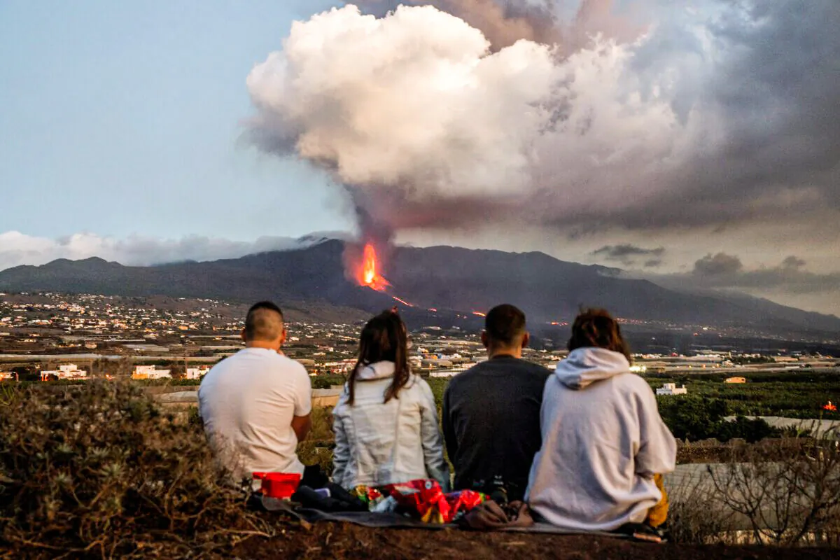 Residents watch as lava flows from a volcano as it continues to erupt on the Canary island of La Palma, Spain, on Oct. 26, 2021. (Emilio Morenatti/AP Photo)