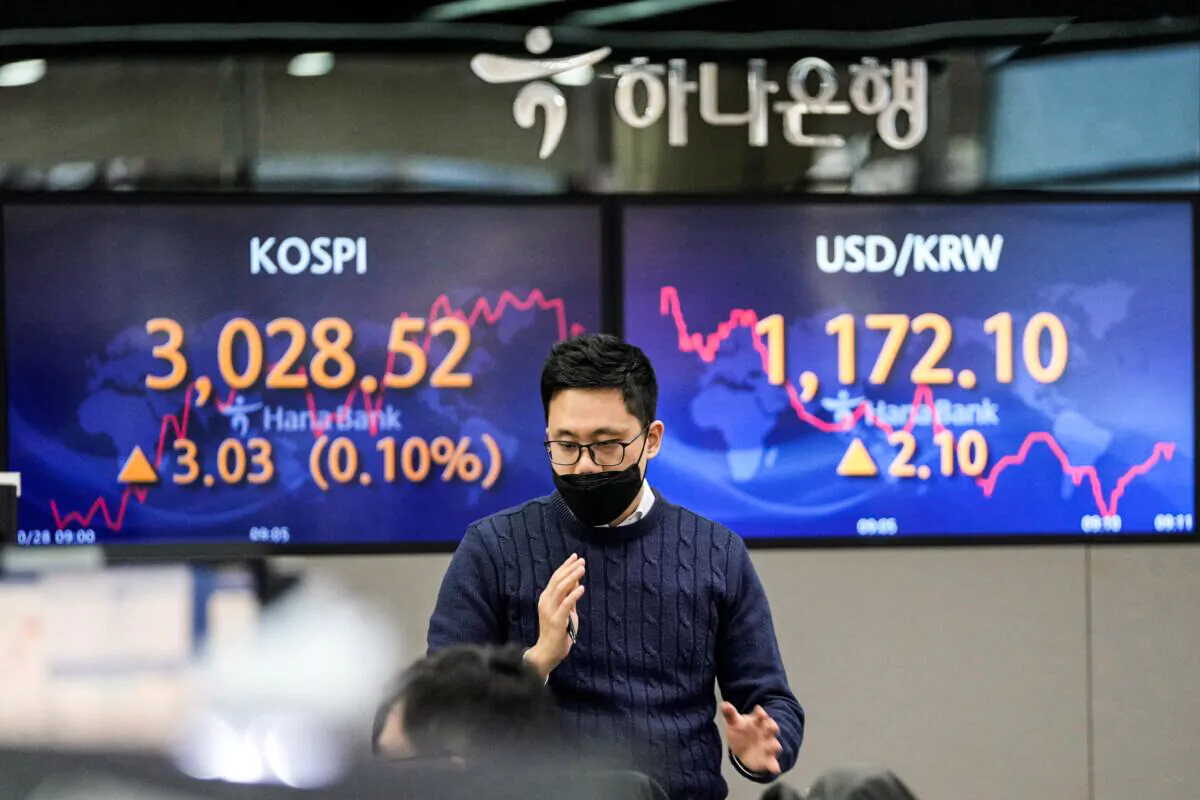 A currency trader walks by the screens showing the Korea Composite Stock Price Index (KOSPI) (L), and the foreign exchange rate between U.S. dollar and South Korean won at a foreign exchange dealing room in Seoul, South Korea on Oct. 28, 2021. (Lee Jin-man/AP Photo)
