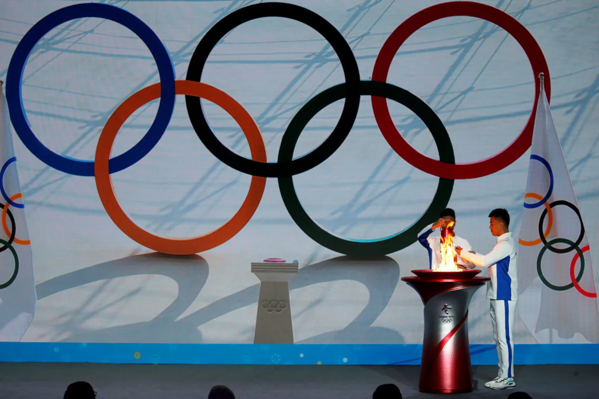 Participants transfer the Olympic flame from a cauldron at the ceremony to welcome the flame for the Beijing 2022 Winter Olympics, in Beijing, China, on Oct. 20, 2021.(Tingshu Wang/Reuters)
