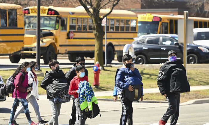 Students cross the street on their way to school in Mississauga, Ontario, on April 1, 2021. (Nathan Denette/The Canadian Press)