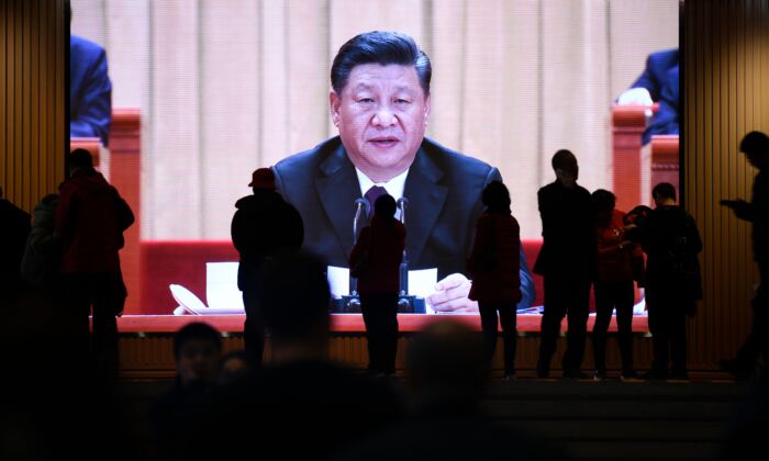 People walk past a screen showing video footage of Chinese leader Xi Jinping at the National Museum of China in Beijing on Feb. 27, 2019. (Wang Zhao/AFP via Getty Images)