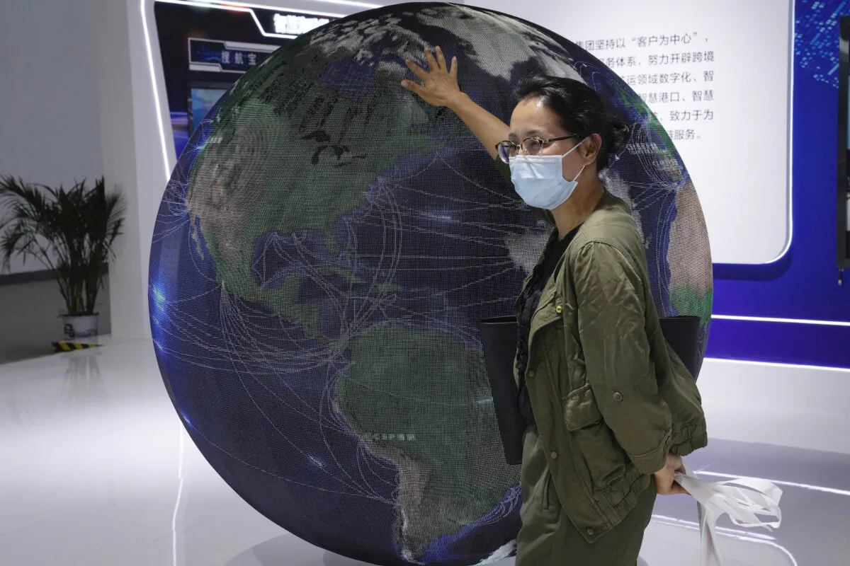 A trade show visitor places her hand on a globe in Beijing, China, September 7, 2021. (Ng Han Guan/AP Photo)