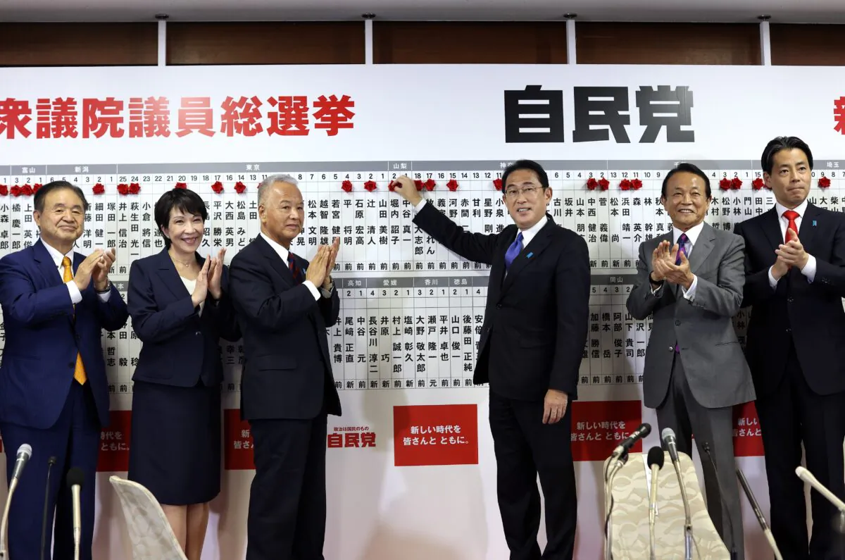 Japan's Prime Minister and ruling Liberal Democratic Party leader Fumio Kishida (3rd-right) poses with key party members as he puts rosettes by successful general election candidates' names on a board at the party headquarters in Tokyo, Japan, on Oct. 31, 2021. (Behrouz Mehri/Pool via AP)