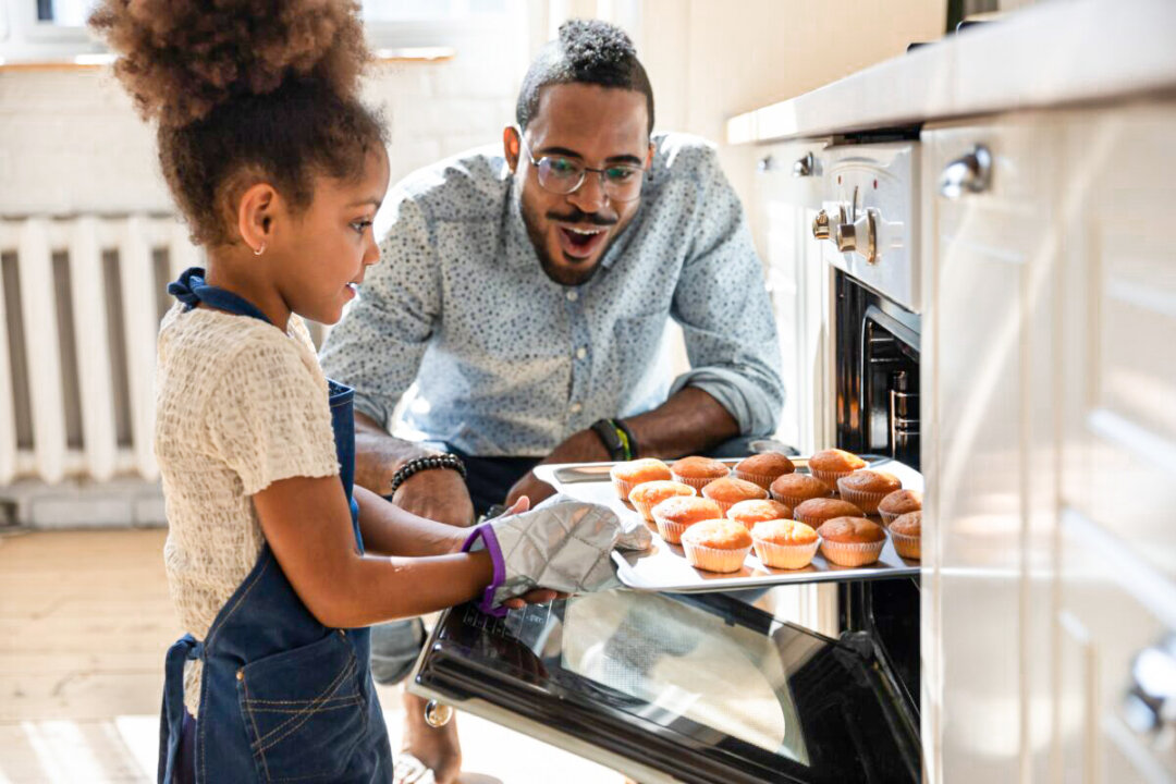 Wow, looks great! Excited caring millennial african dad or grown elder brother watching concentrated small black daughter or younger preteen sister taking pan with self baked tasty muffins out of oven