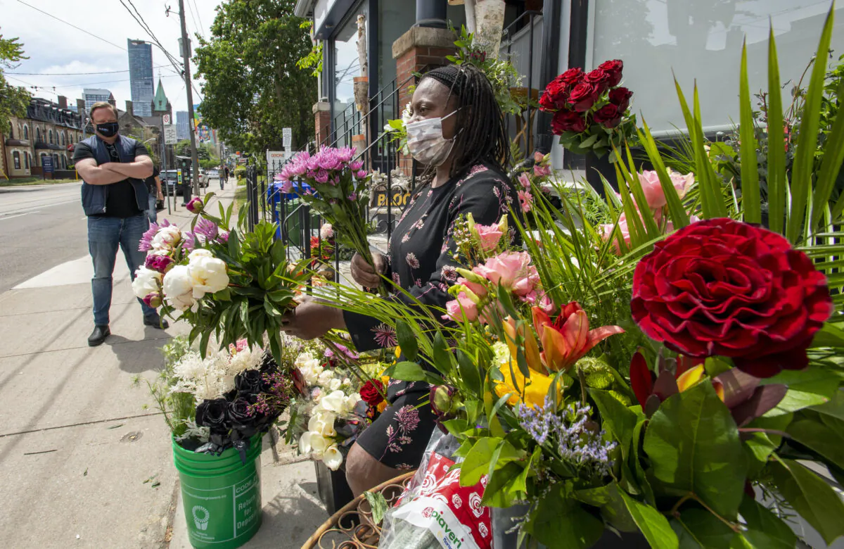 A florist and business owner makes bouquets on the sidewalk in front of her shop in Toronto on May 29, 2021. (The Canadian Press/Frank Gunn)