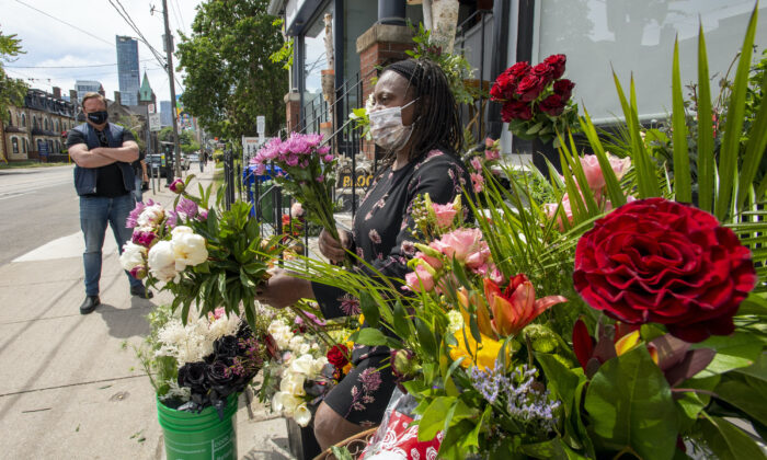 A florist and business owner makes bouquets on the sidewalk in front of her shop in Toronto on May 29, 2021.  (The Canadian Press/Frank Gunn)