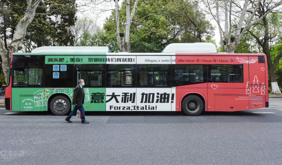 A man walks past a bus with a message supporting Italy in their efforts against the COVID-19 coronavirus in Hangzhou in China's eastern Zhejiang Province on March 24, 2020. (STR/AFP via Getty Images)
