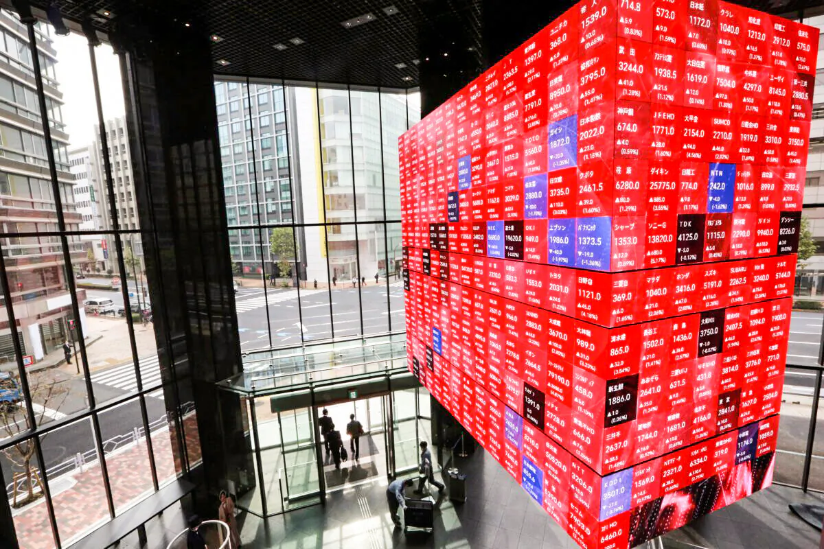 People walk below an electronic stock board at a conference hall in Tokyo, Japan on Nov. 1, 2021. (Koji Sasahara/AP Photo)