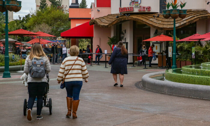 2021 年 2 月 1 日，人们走过加利福尼亚州阿纳海姆的迪士尼市中心购物和餐饮区。（John Fredricks/媒体时报）
