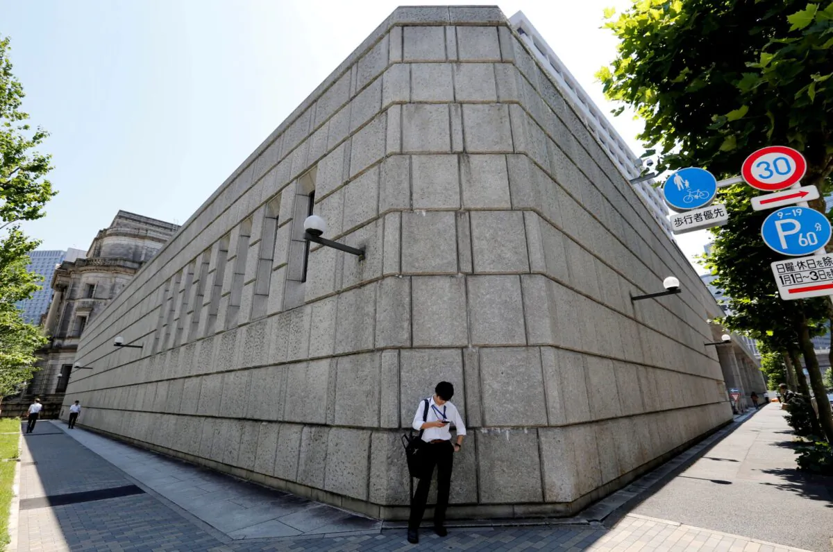 A man looks at a mobile phone in front of the Bank of Japan building in Tokyo, Japan, on June 16, 2017. (Toru Hanai/Reuters)