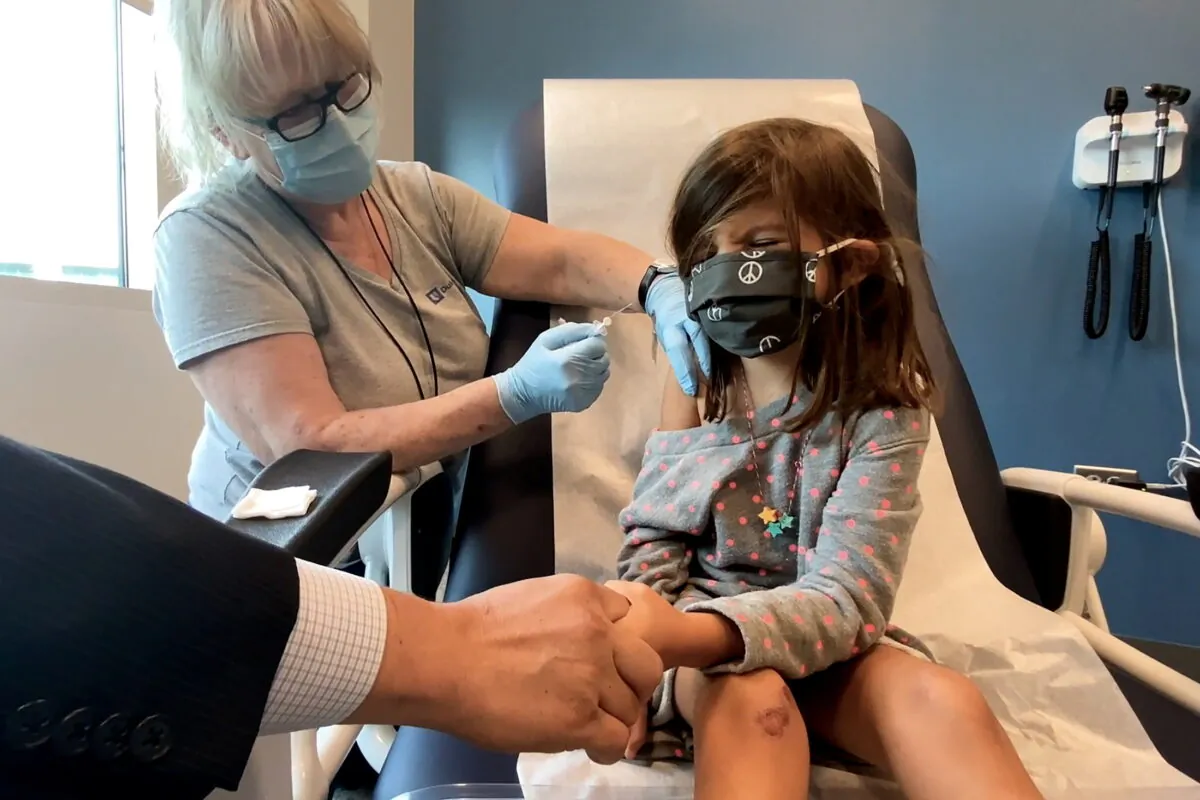 In this image from video, a 5-year-old girl holds her father's hand while getting the Pfizer COVID-19 vaccine during a trial at Duke University in Durham, N.C., on Sept. 28, 2021. (Shawn Rocco/Duke University via Reuters)