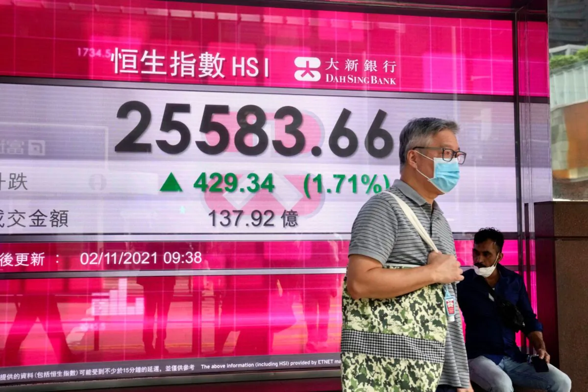 A man wearing a face mask walks past a bank's electronic board showing the Hong Kong share index in Hong Kong on Nov. 2, 2021. (Kin Cheung/AP Photo)