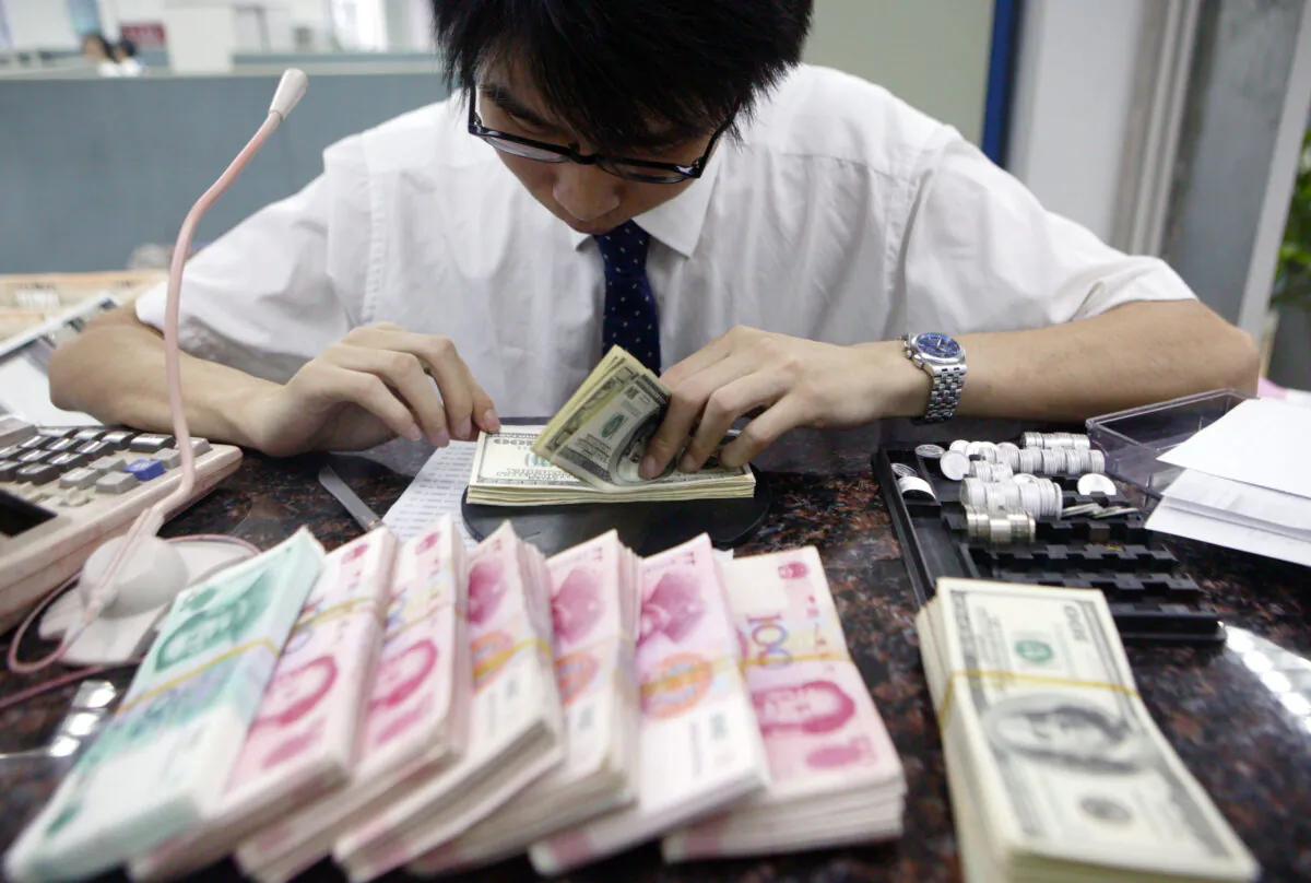 A clerk counts stacks of Chinese yuan and U.S. dollars at a bank, in Shangai, China, on July 22, 2005.  (China Photos/Getty Images)