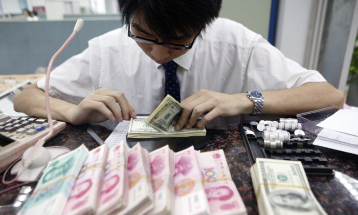 A clerk counts stacks of Chinese yuan and U.S. dollars at a bank in Shanghai on July 22, 2005. (China Photos/Getty Images)