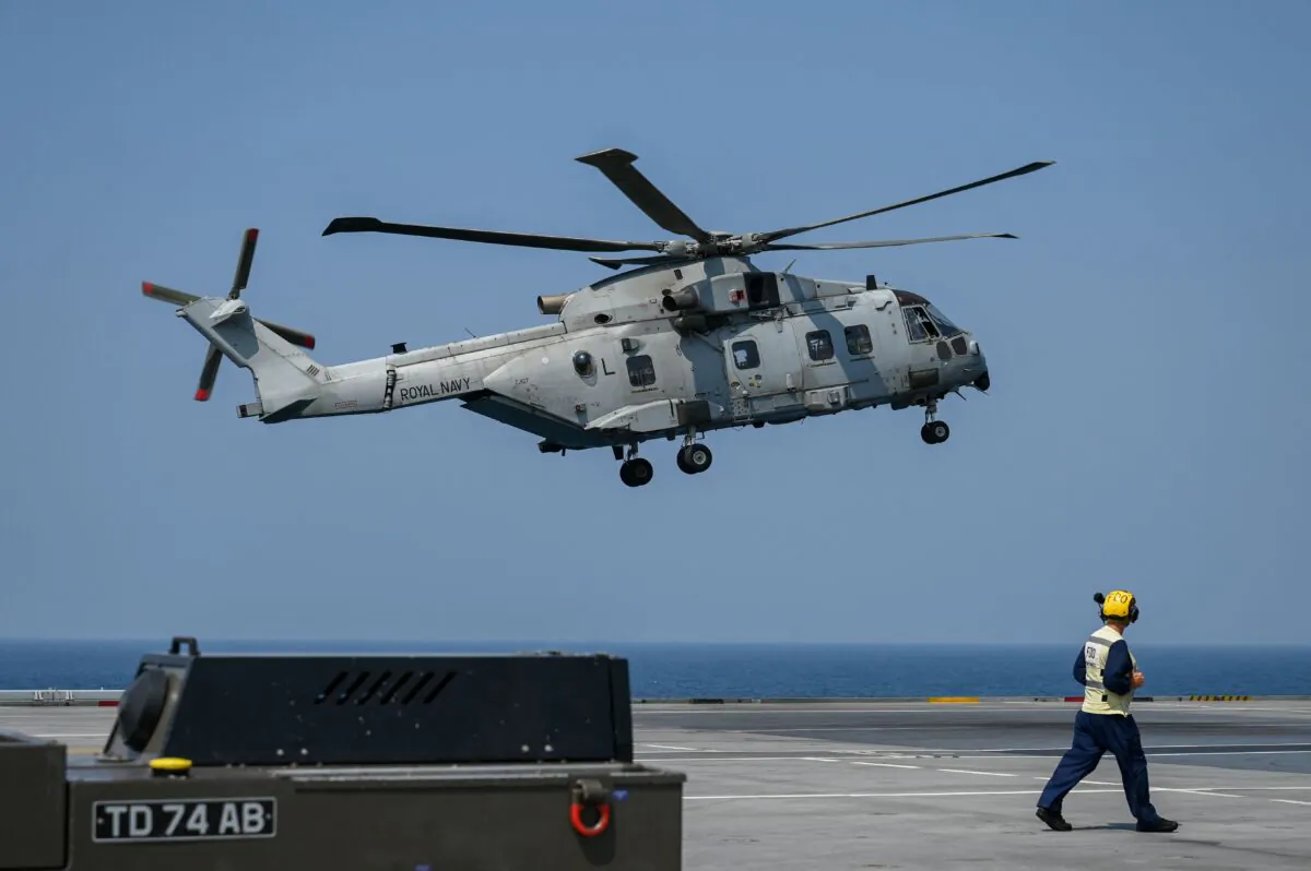A British serviceman watches as a helicopter lands on the flight deck of UK Carrier Strike Groups HMS Queen Elizabeth in the Arabian Sea, off Mumbai coast on October 21, 2021. (Photo by Punit  Paranjpe/AFP via Getty Images)