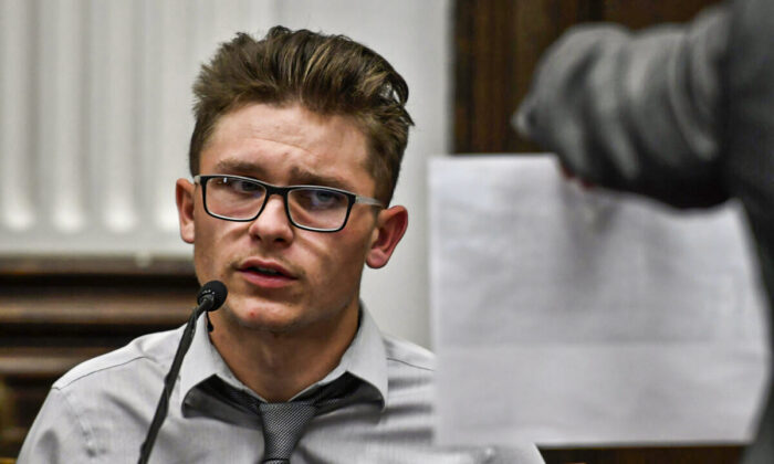 Dominick Black looks at a photograph held by Assistant District Attorney Thomas Binger, where he along with Kyle Rittenhouse and a group of others posed on Aug. 25, 2020, during Kyle Rittenhouse's trial at the Kenosha County Courthouse in Kenosha, Wis, on Tuesday, Nov. 2, 2021. Rittenhouse is accused of killing two people and wounding a third during a protest over police brutality in Kenosha, last year.  (Sean Krajacic/ Kenosha News via AP, Pool)