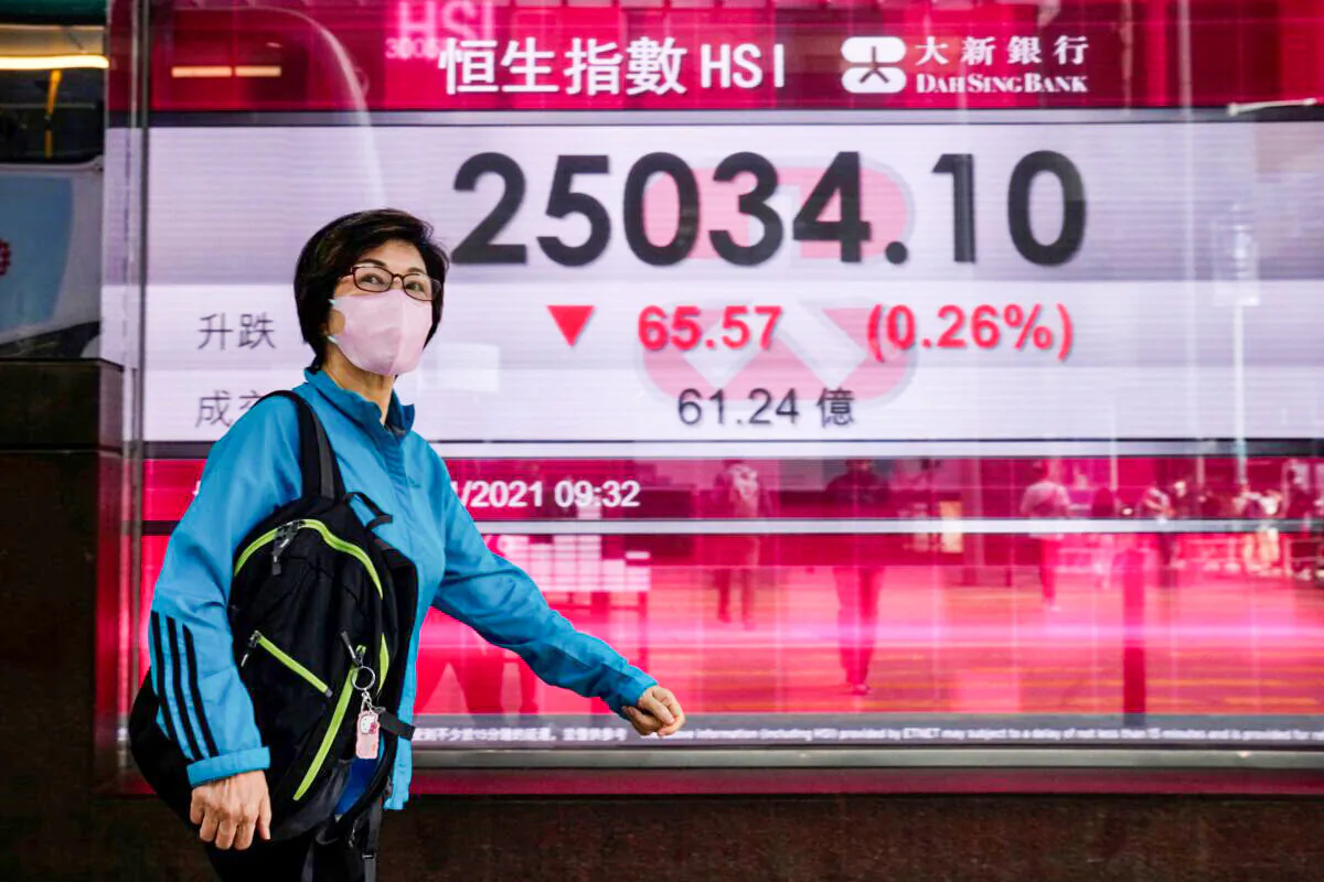 A woman wearing a face mask walks past a bank's electronic board showing the Hong Kong share index in Hong Kong on Nov. 3, 2021. (Kin Cheung/AP Photo)