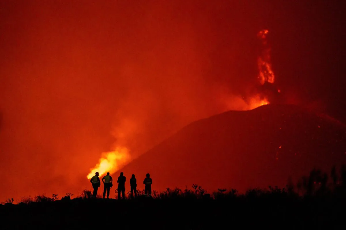 Police officers and emergency personnel look as lava flows from a volcano as it continues to erupt on the Canary island of La Palma, Spain, on Nov. 2, 2021. (Emilio Morenatti/AP Photo)