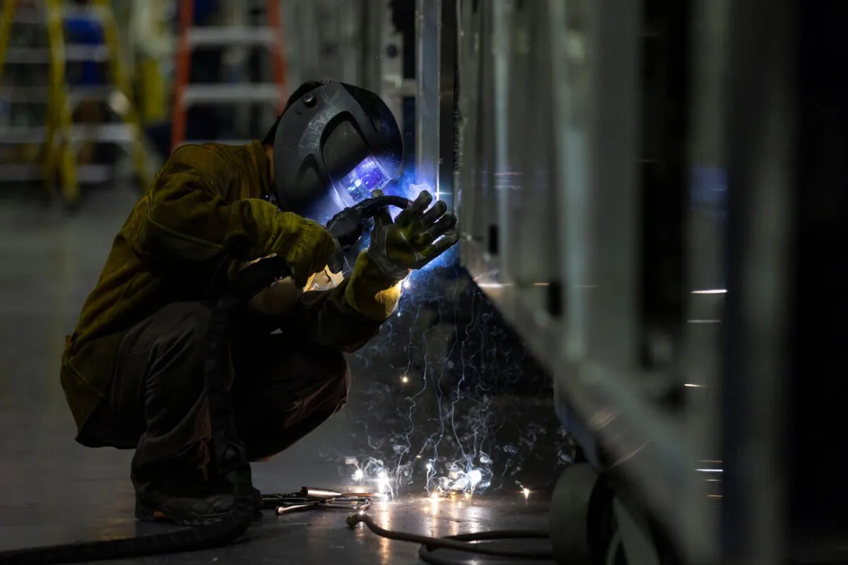 A welder works while building a bus frame at the BYD electric bus factory in Lancaster, Calif., on July 1, 2021. (Mike Blake/Reuters)