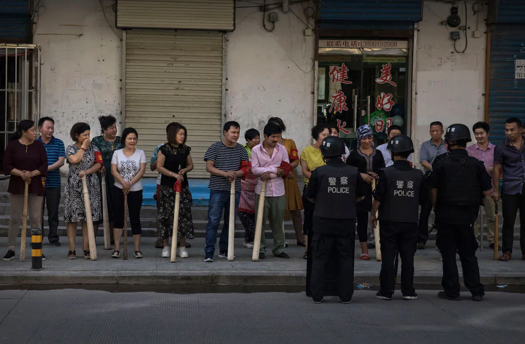 A mix of ethnic Uyghur and Han shopkeepers hold large wooden sticks as they are trained in security measures in the far western Xinjiang Province, China, on June 27, 2017. (Kevin Frayer/Getty Images)