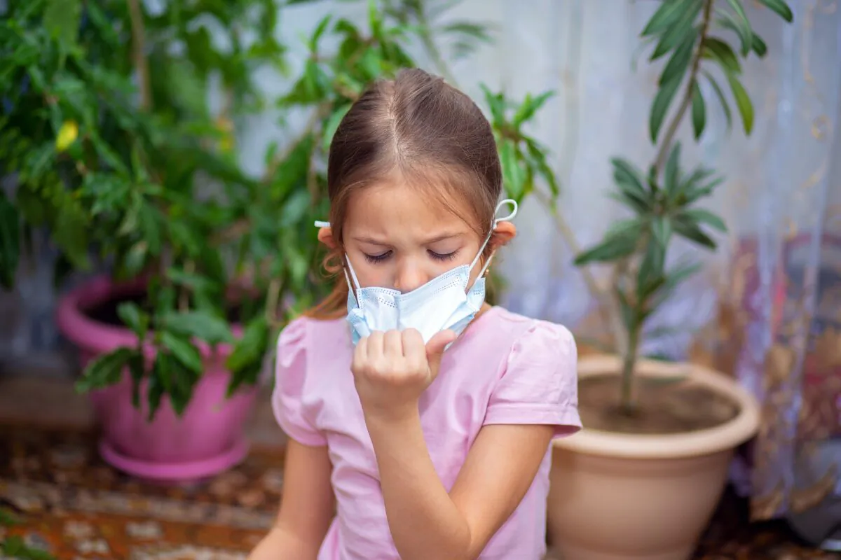 A girl pulls at a mask she is wearing. (borisenkoket/Shutterstock)
